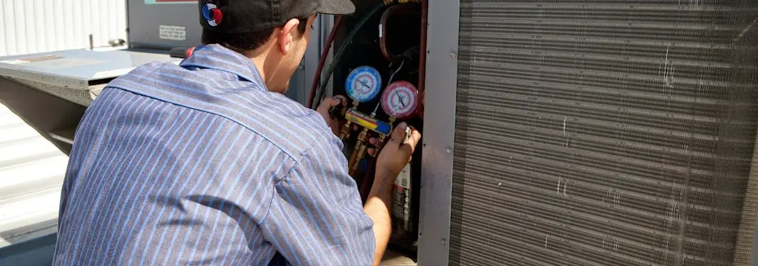 HVAC technician servicing a condenser unit in West Bend
