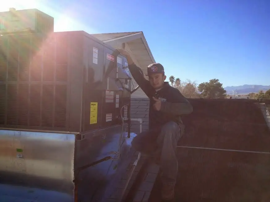HVAC technician performing AC Tune-Up on a rooftop unit in West Bend